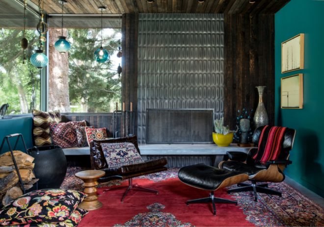 teal painted room with dark leather chairs and colorful patterned rug