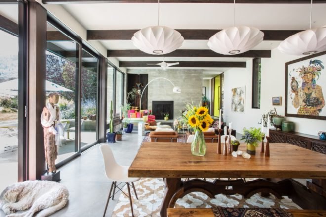 wood dining table in foreground, tan leather chairs and colorful window seat in background