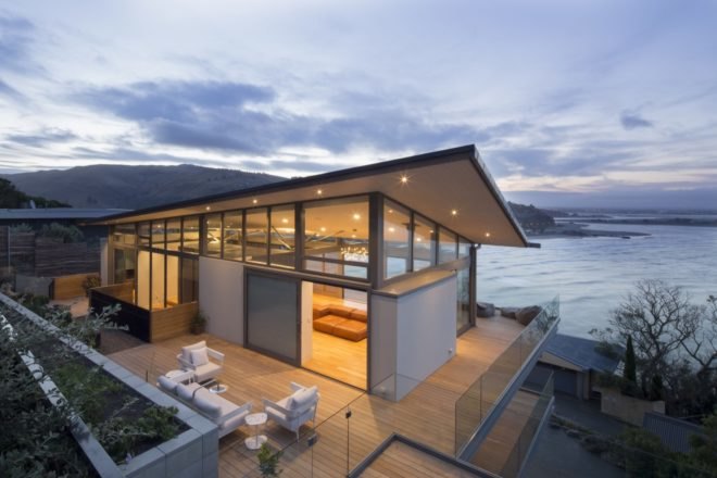 timber and stone home facing the ocean at dusk