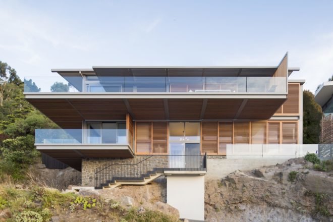 stone home with timber slat screens over large glass windows