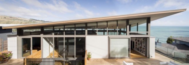 home with large balcony and sloped roof by the ocean