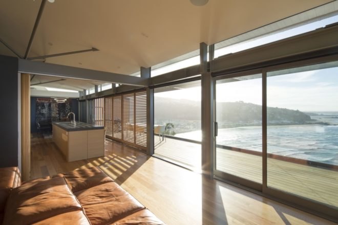 tan leather couch facing glass walls and outdoor balcony with ocean views