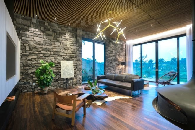 living room with black leather couch, dark wood floors, and stone and glass walls