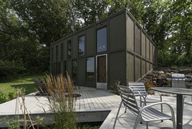 black cube home with light gray timber patio with several seats