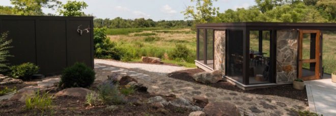 cropped close-up of black cube home and smaller black and stone screened-in porch