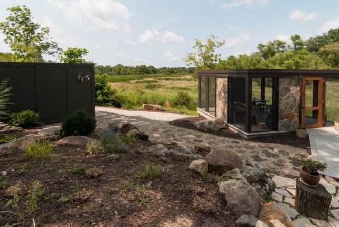 black cube home and smaller black and stone screened-in porch