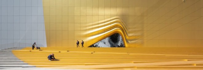 cropped close-up of white and gold building with opening that looks like rippled fabric