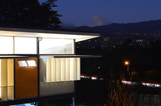 open solar shades on a home at night