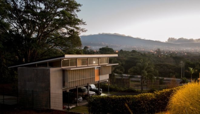 angled view of white home on stilts with volcanoes in background at dusk