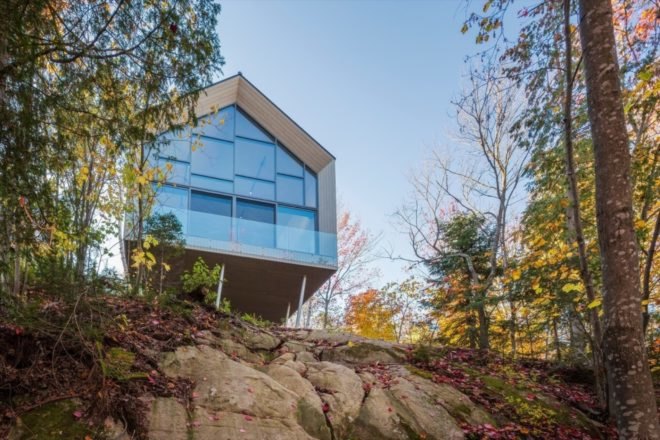 gabled studio building with glass wall on a cliff