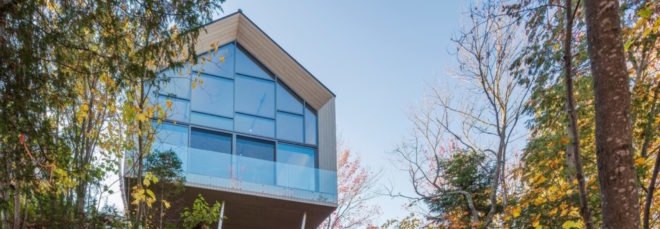 gabled studio building with glass wall on a cliff