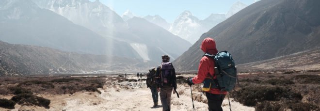 cropped close-up of people hiking a trail with mountains in the background