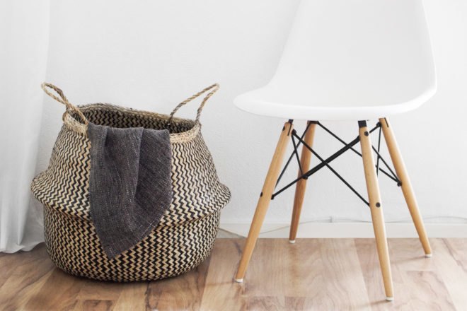 patterned basket with blanket inside next to a white chair