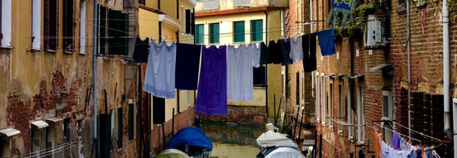 cropped close-up of blue clothes hanging on a line above a canal