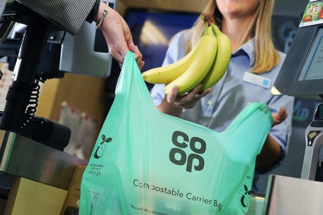 Person putting bananas in a green compostable bag