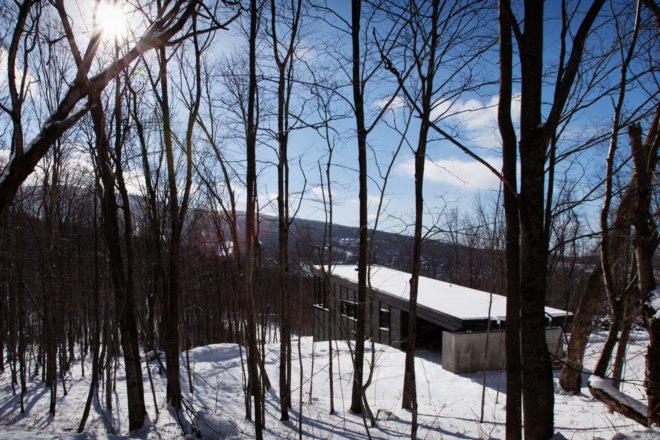 black timber home with snow-covered green roof