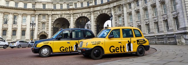 cropped close-up of two yellow and black taxis in front of Admiralty Arch in London