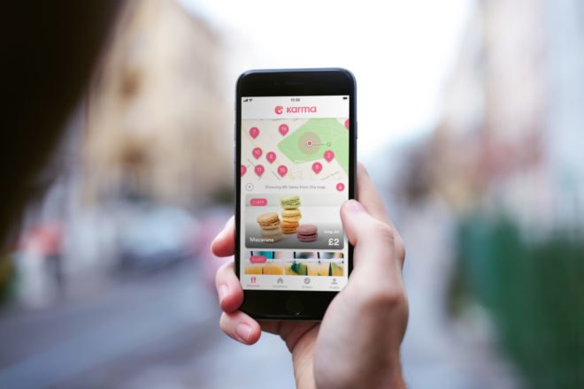 hand holding phone with food app on the screen and blurry city in the background