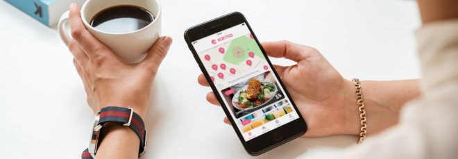 cropped close-up of person holding cup of coffee and phone using app to order food