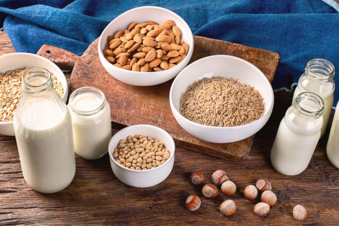 Glass jars of milk and bowls of nuts, rice and oats