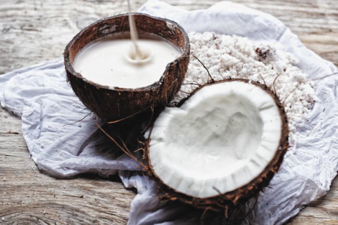 milk in a rustic bowl next to a split open coconut
