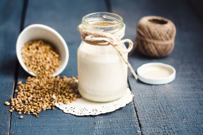 milk in a glass jar with bowl of hemp seeds next to it