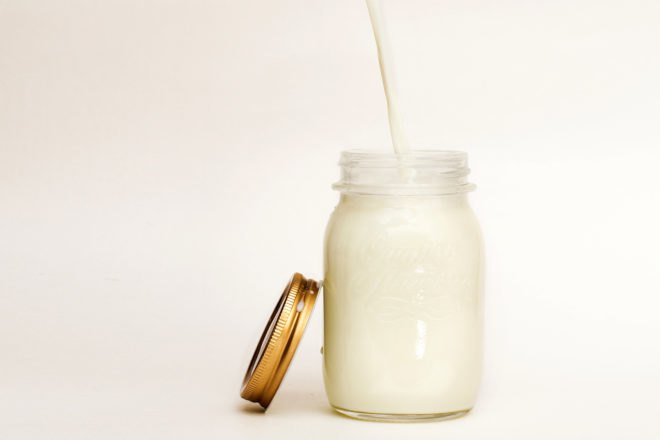 off-white milk being poured into a glass jar