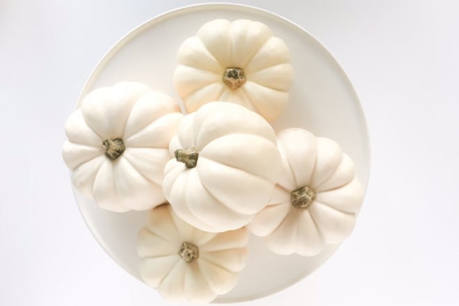 white pumpkins on a white cake stand on a white background