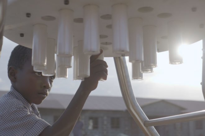 child grabbing tube-shaped battery from a solar-powered charging station