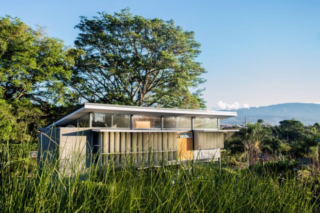 angled view of house with sloped roof and solar shades with volcano in background
