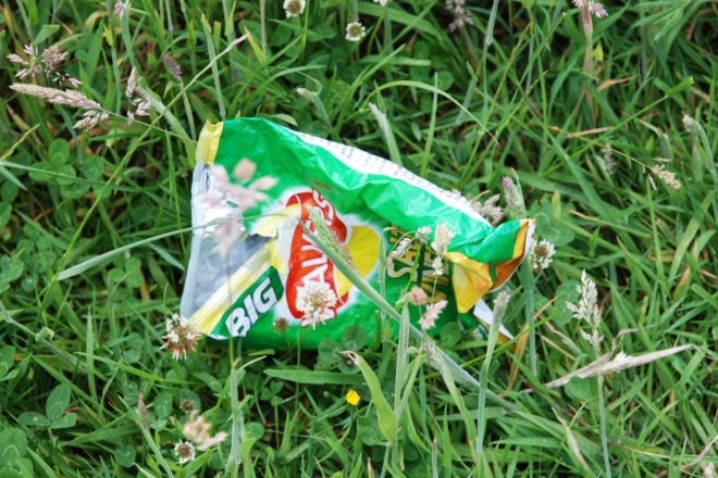 empty green Walkers potato chip bag in the grass