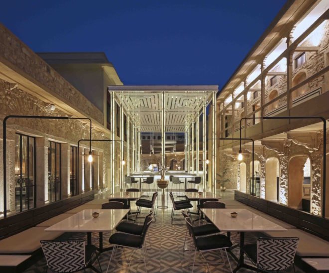 stone buildings with white tables and well-lit bar space between the buildings