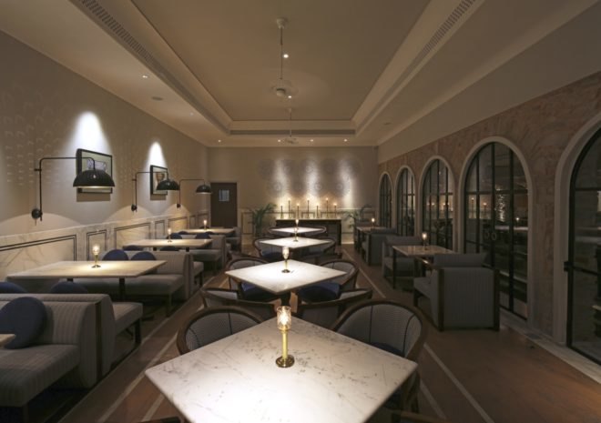 indoor dining area with marble tables, gray seating and exposed stone walls