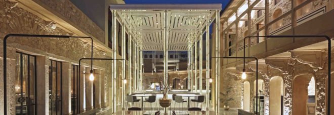 stone buildings with white tables and well-lit bar space between the buildings