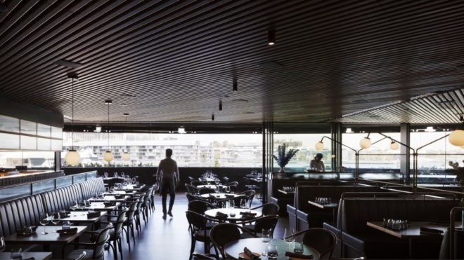 restaurant with glass walls, dark ceilings and dark furnishings