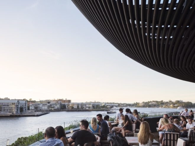 people dining on a balcony overlooking water