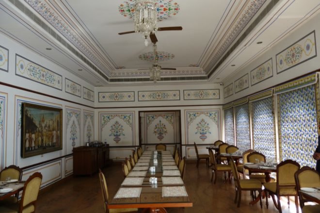 before image of old wood tables and chairs in white room with fine painting details on the wall