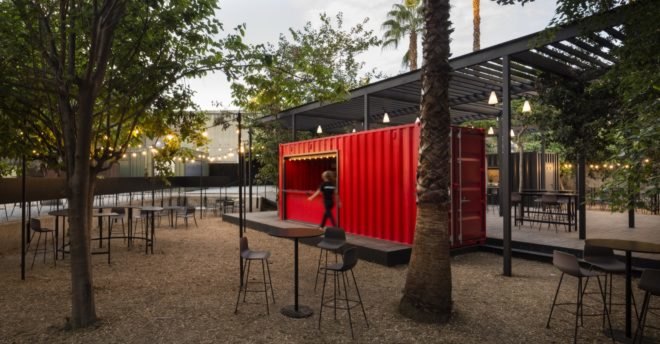 bright red shipping container surrounded by dining tables and chairs