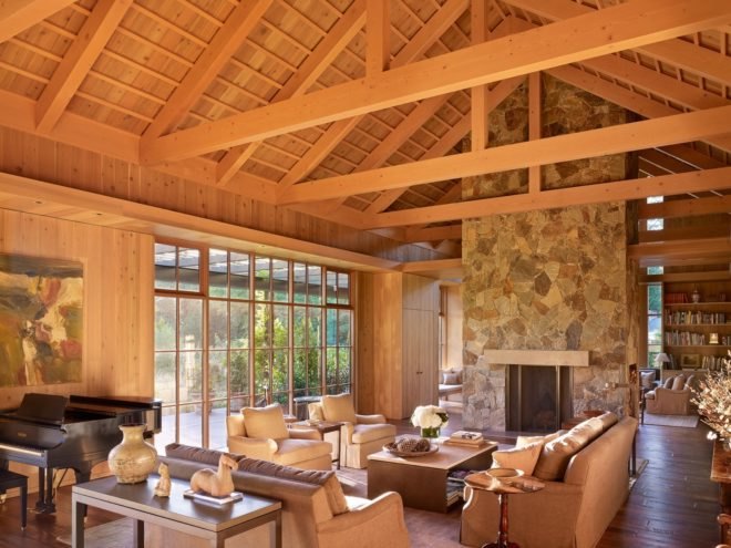timber-lined living room with several gray couches and chairs and exposed timber ceiling beams