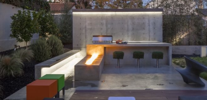 outdoor kitchen with grass-covered barstools and concrete fire pit