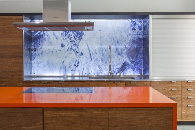 kitchen with blue marbled backsplash, wood cabinets, and bright orange island