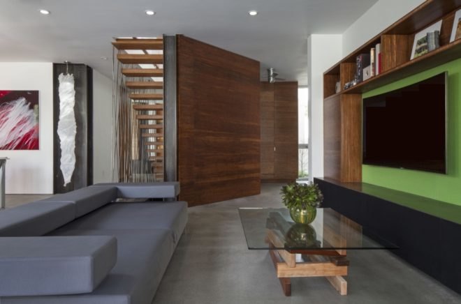 living space with gray couch, glass coffee table and wall-mounted tv on a green entertainment center