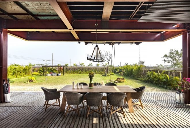 wood table and wicker chairs on outdoor deck facing gardens