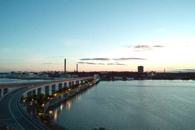 rendering of bridge with glass apartments below and a park on top leading to a city