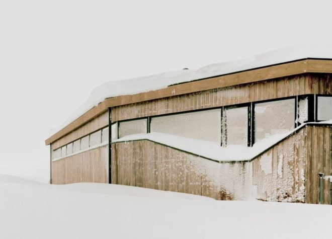 a light wood cabin built into snowy hill