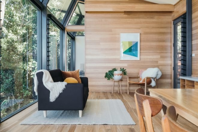 cabin with glass and timber walls and a dark sofa