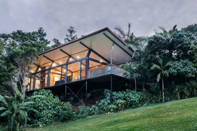elevated glass cabin surrounded by trees