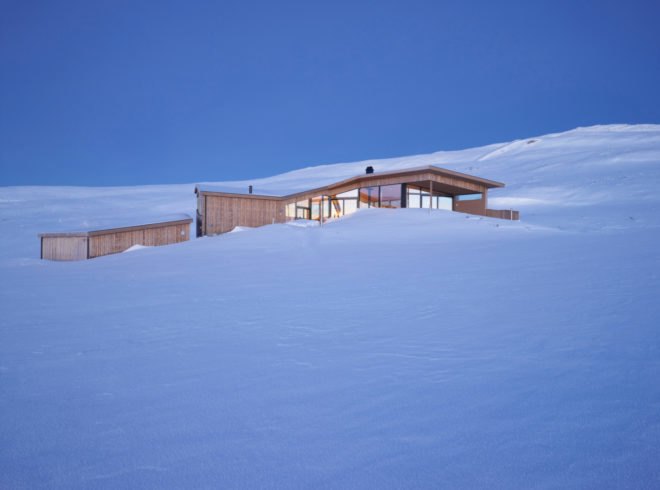 a light wood cabin surrounded by snow