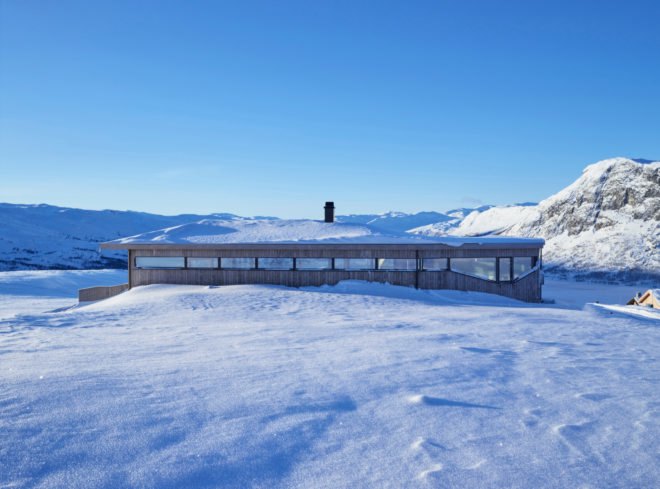 long wood cabin surrounded by snow