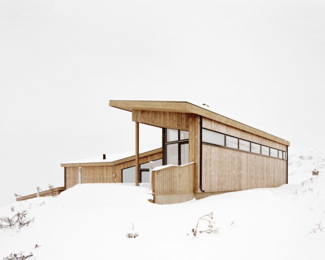 light wood cabin with slanted roof on snowy landscape